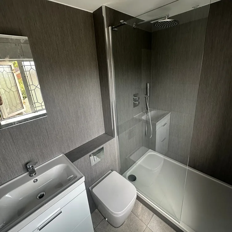 Compact modern bathroom with dark textured walls and walk-in shower