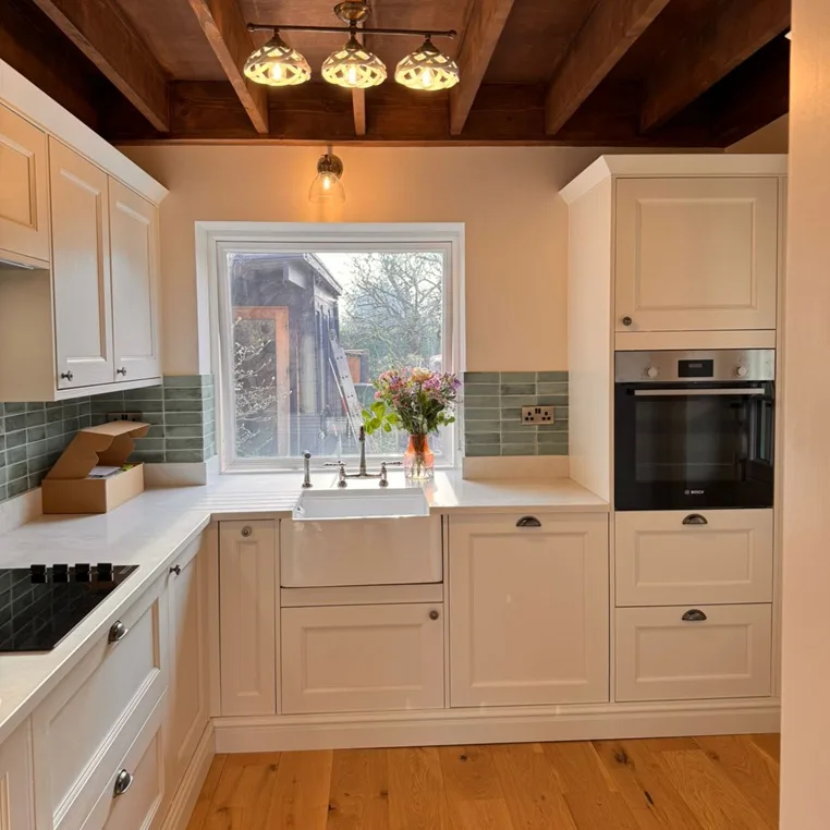 Traditional kitchen with cream cabinets, exposed wooden beams, and green subway tiles
