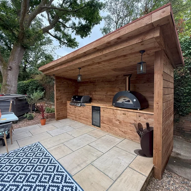 Custom outdoor kitchen with wooden structure, pizza oven, and BBQ area